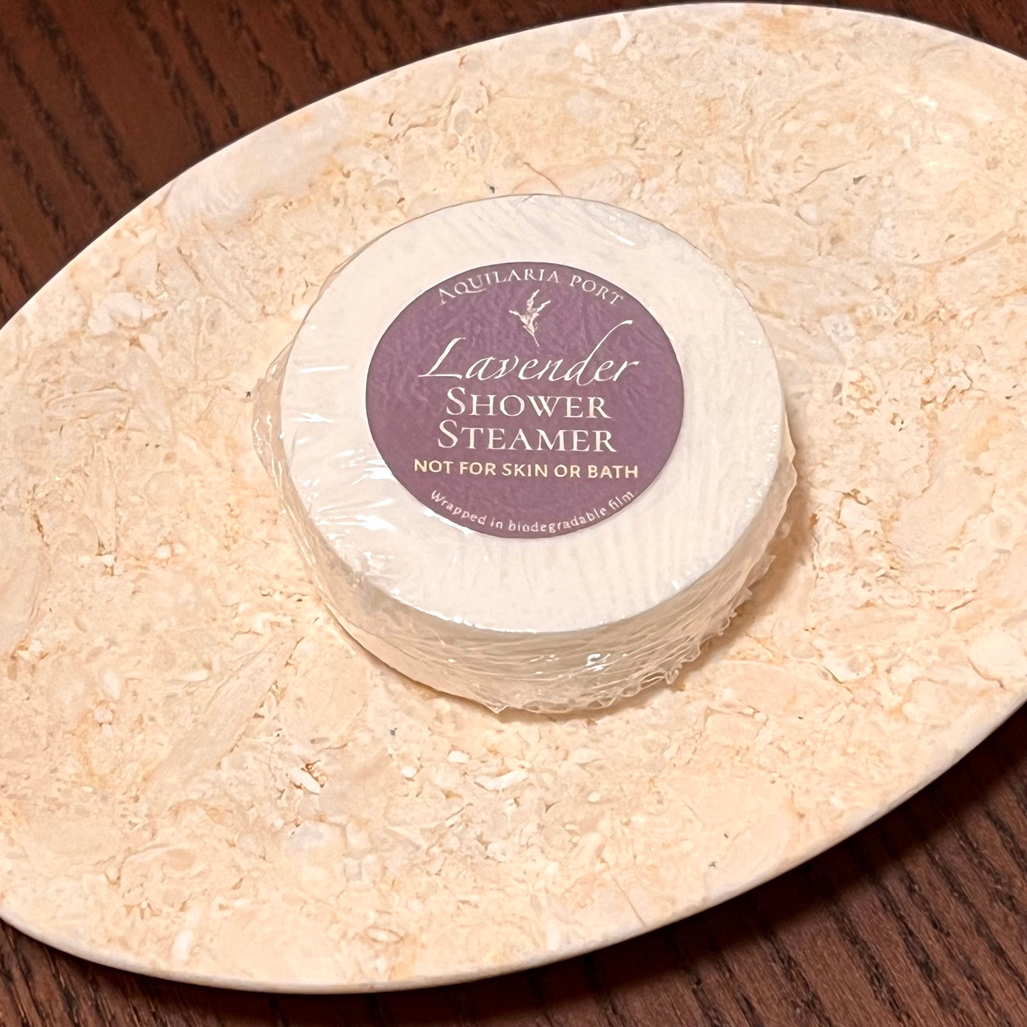 Lavender shower steamer on a stone surface with a purple label.