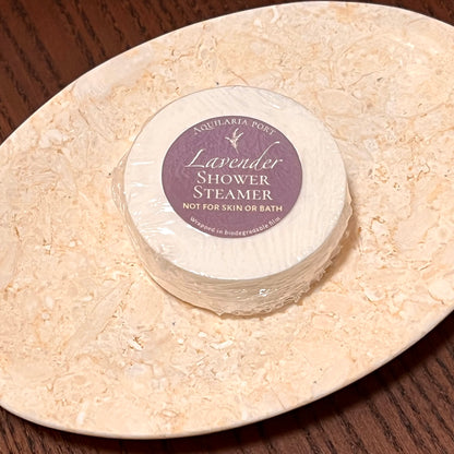 Lavender shower steamer on a stone surface with a purple label.
