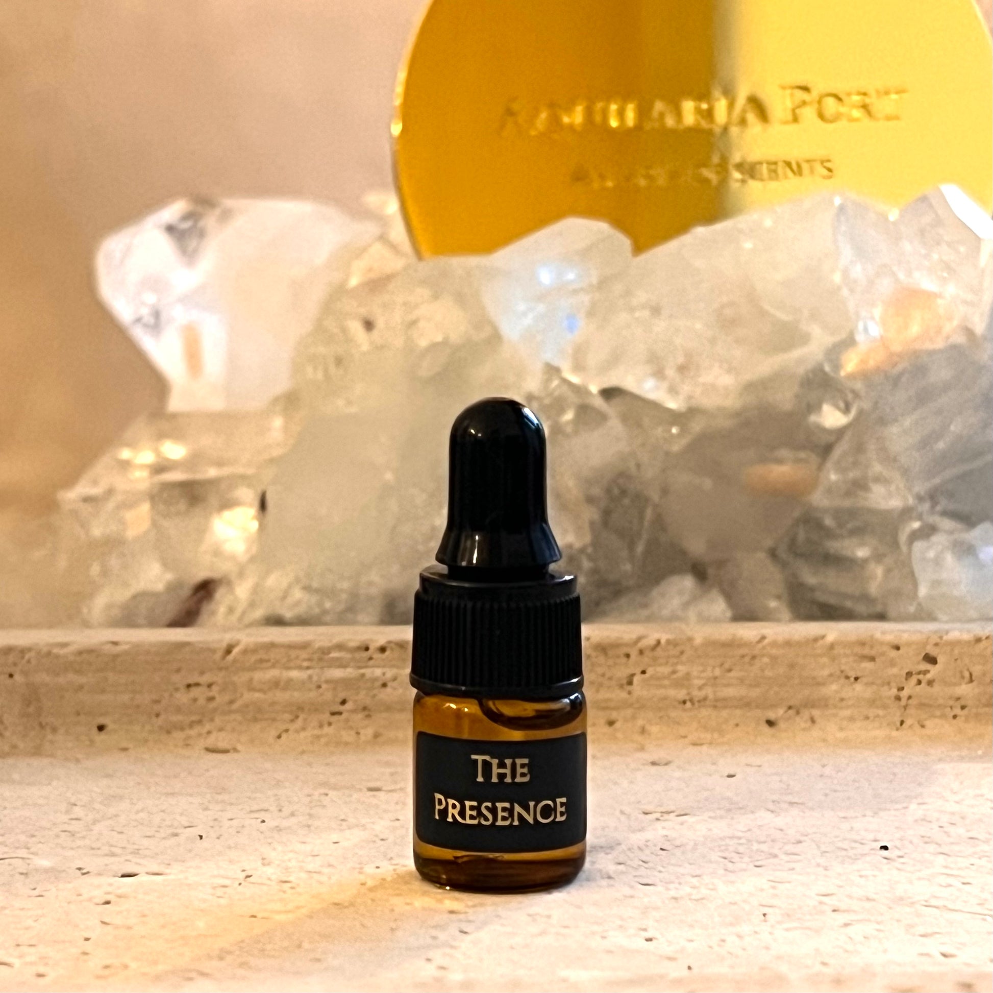 Small bottle labeled 'The Presence' with crystals and a gold disc in the background