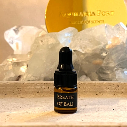 Bottle labeled 'Breath of Bali' with crystals and a gold disc in the background