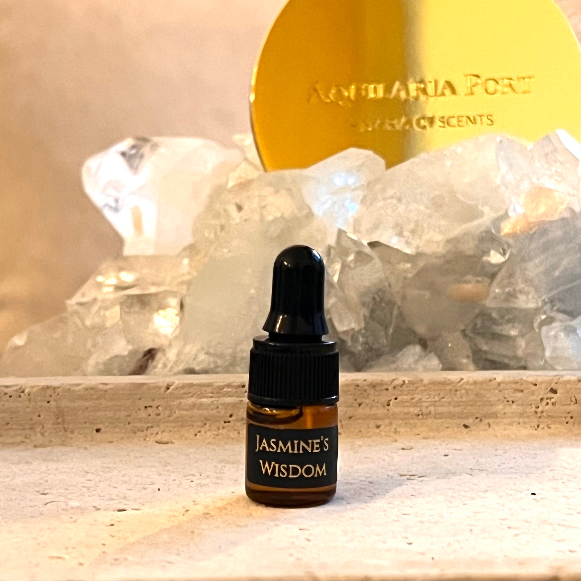 Bottle labeled 'Jasmine's Wisdom' with crystals and a gold disc in the background