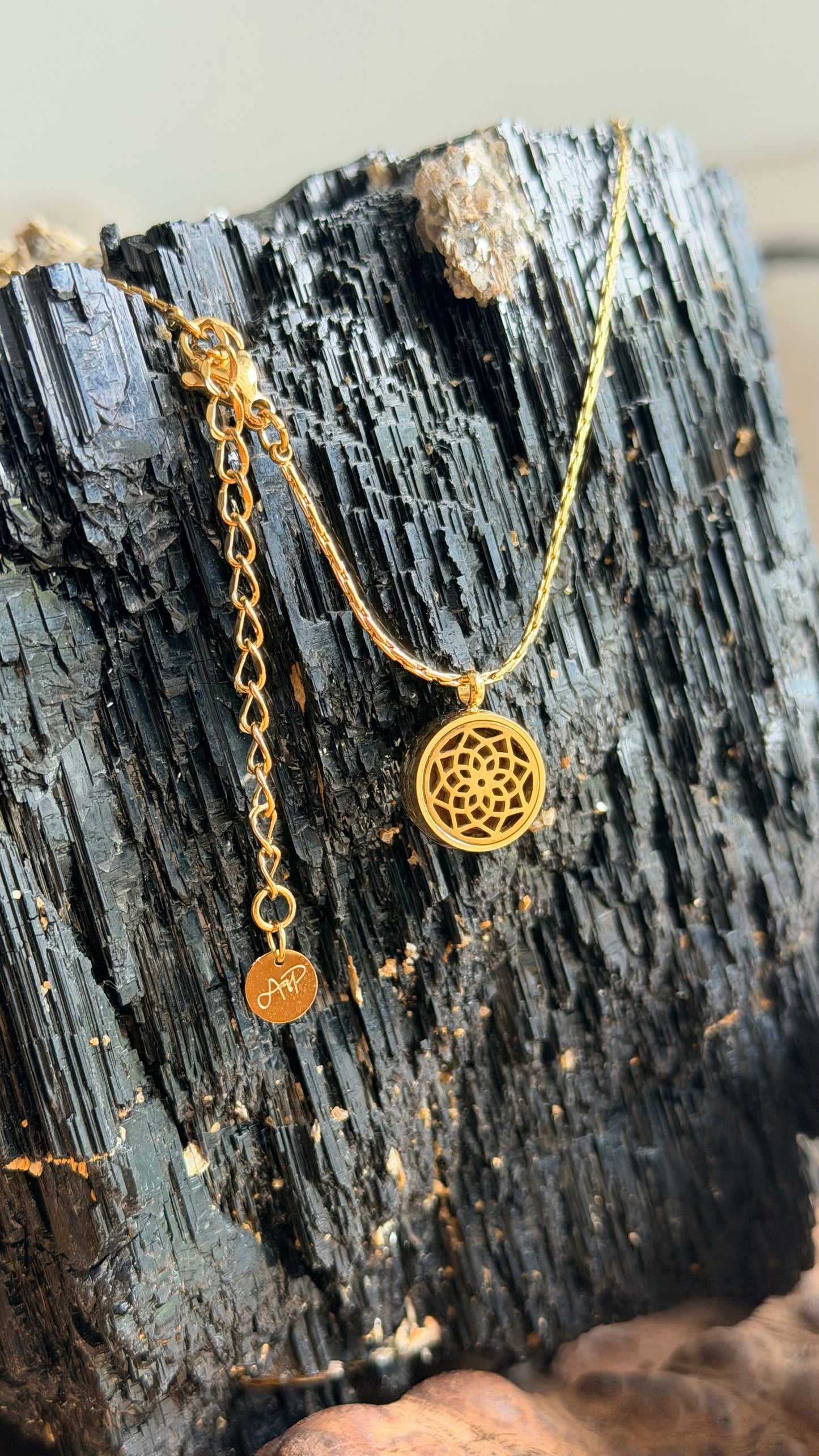Gold necklace with a pendant on a black Tourmaline surface