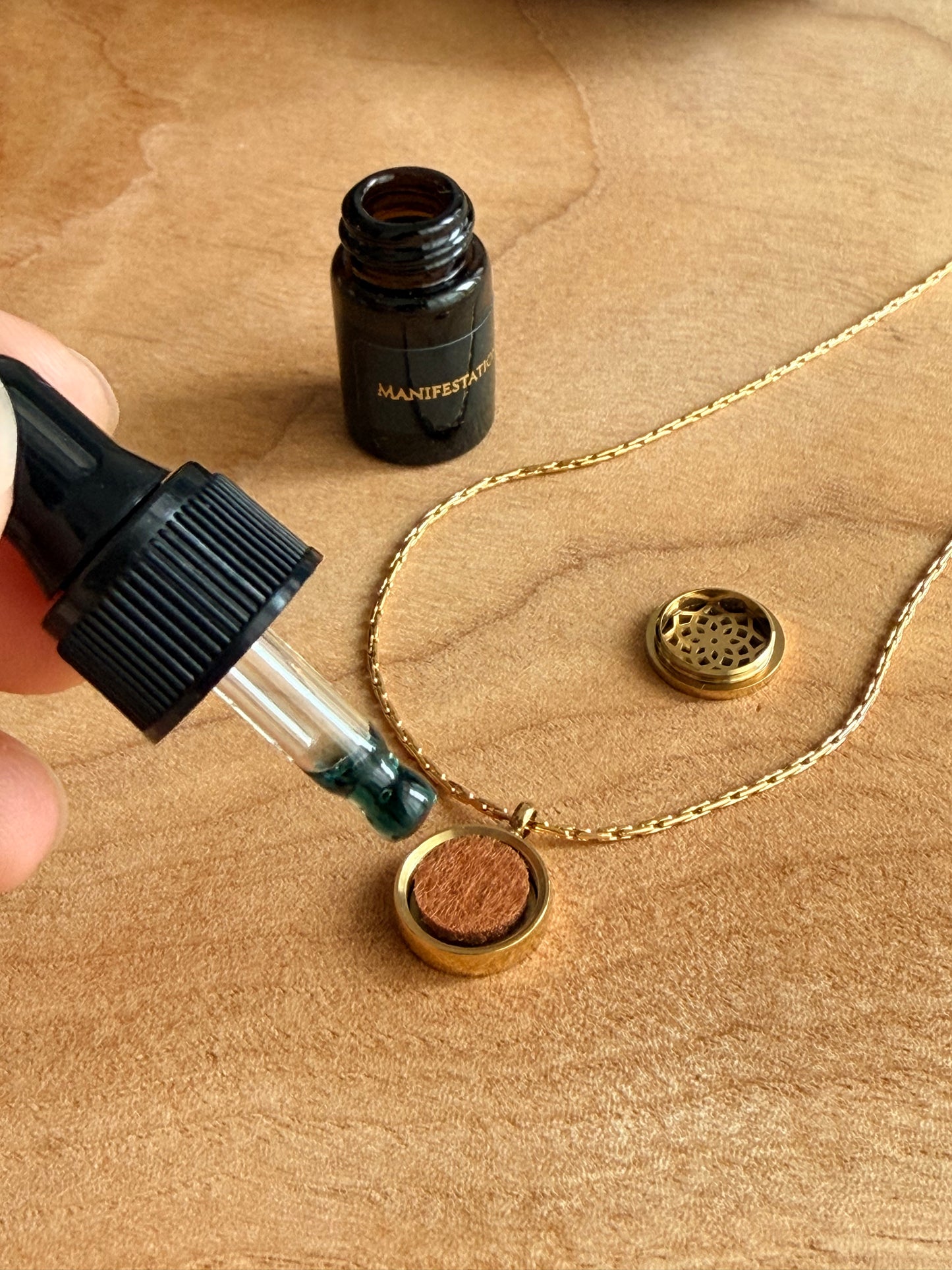 Gold aroma necklace opened revealing a brown cotton pad inside that can absorb the Manifestation Mini Essential Oil.