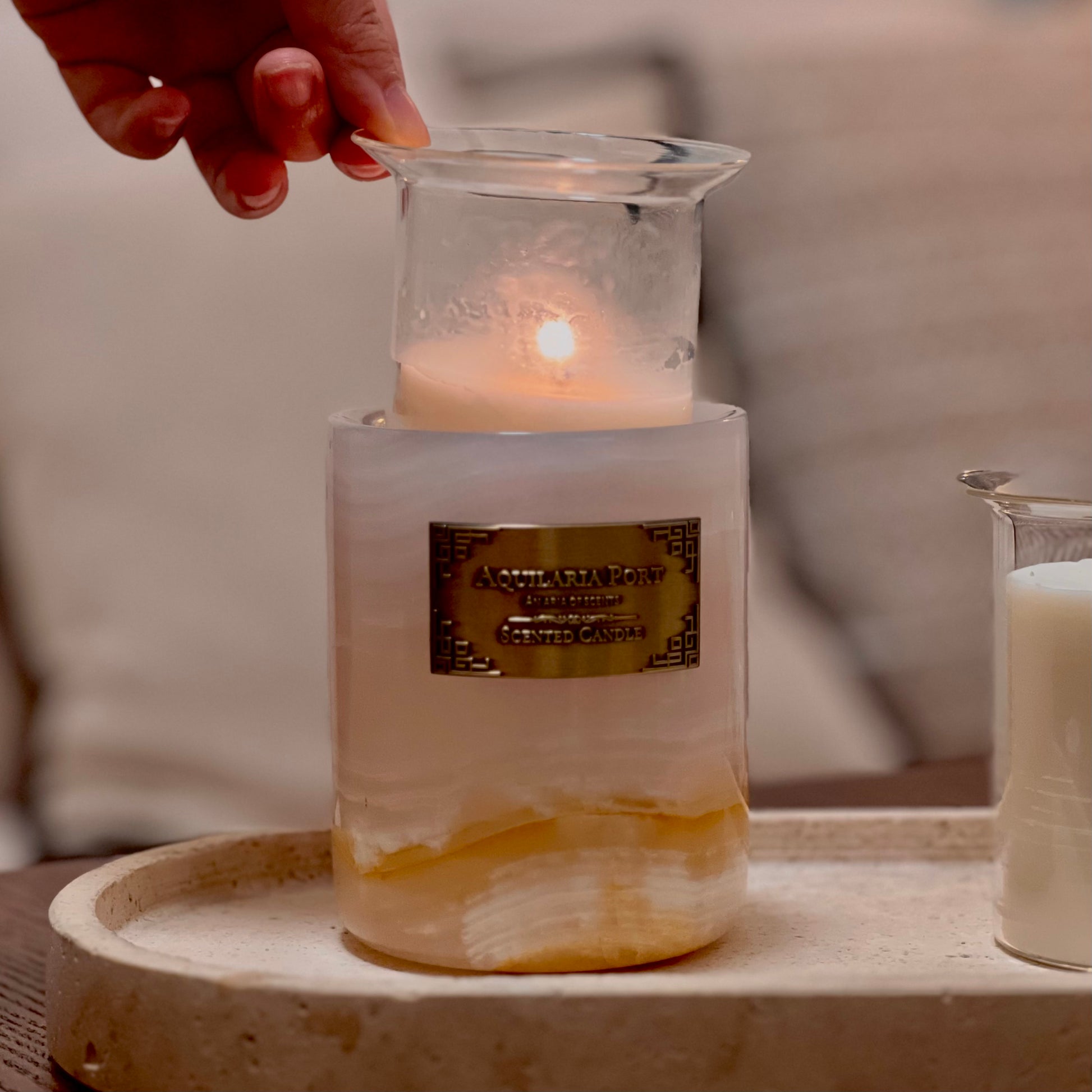 Candle in a glass holder with a label on a marble surface