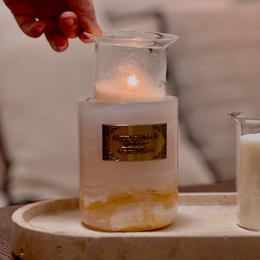 Candle in a glass holder with a label on a marble surface